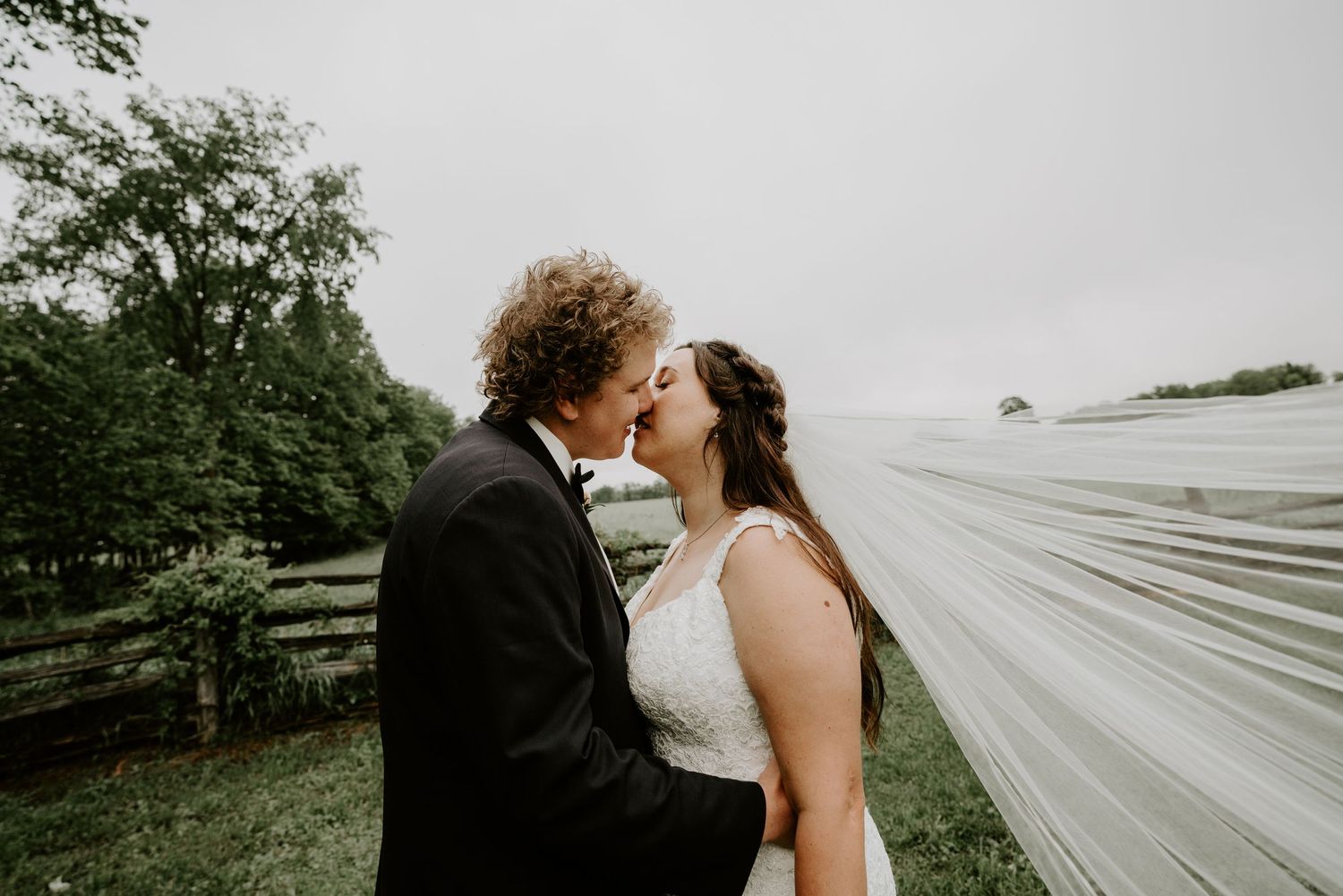 bride and groom kissing with veil blowing in wind