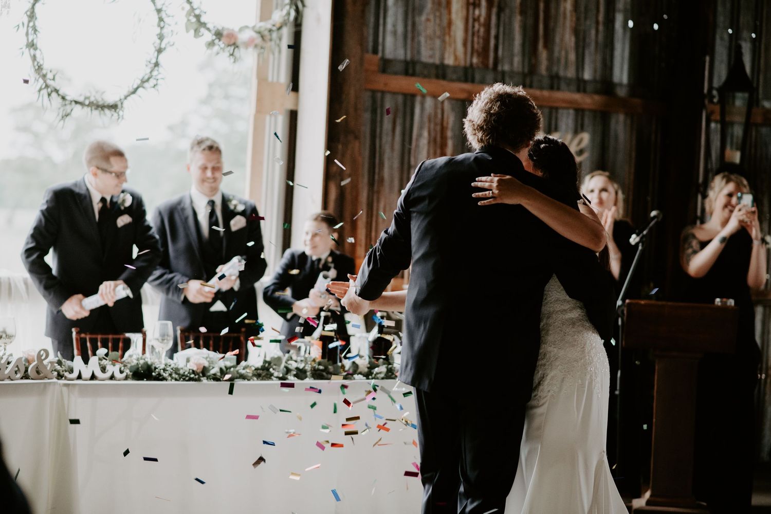 bride and groom dance while groomsmen blast confetti