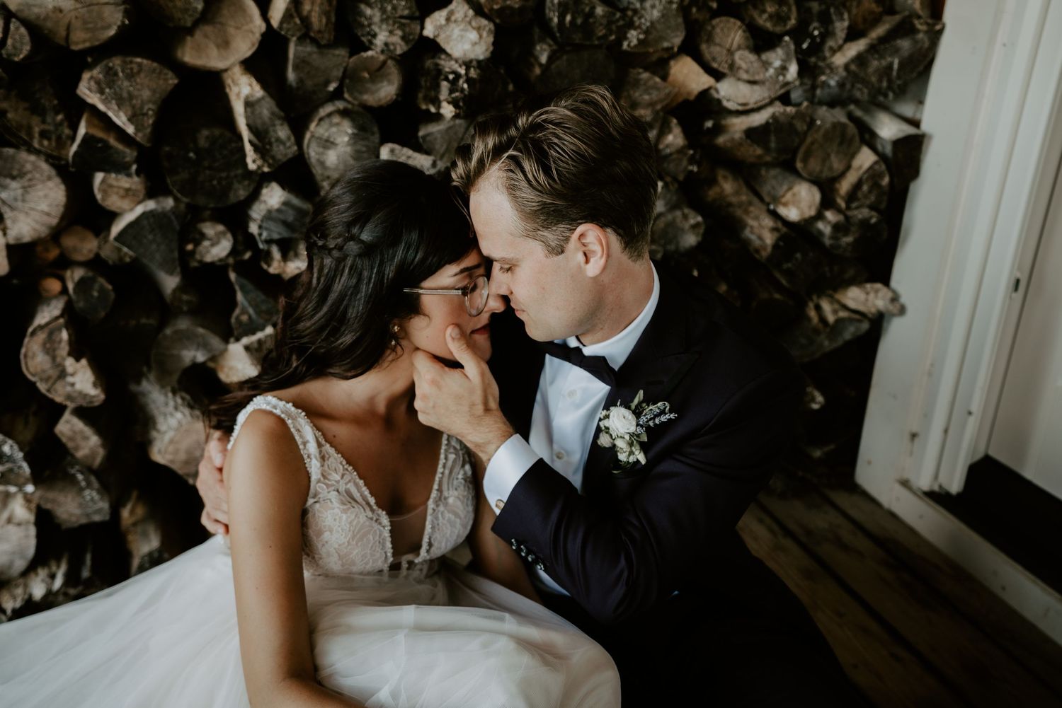 bride and groom by woodpile sitting and snuggling
