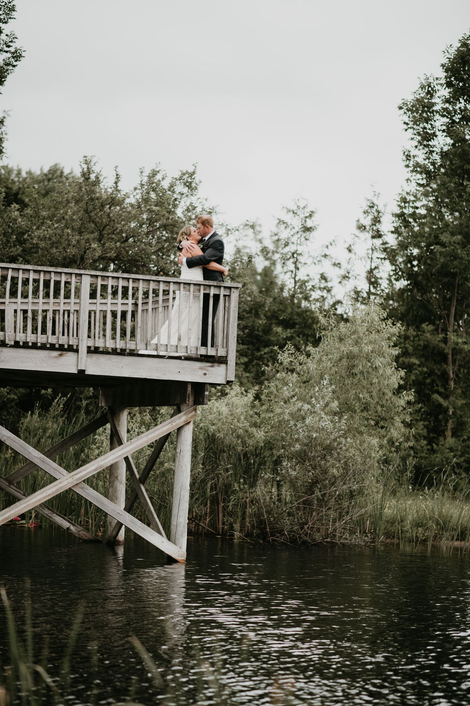bride and groom overlooking pond on a high bridge in Hanover Ontario