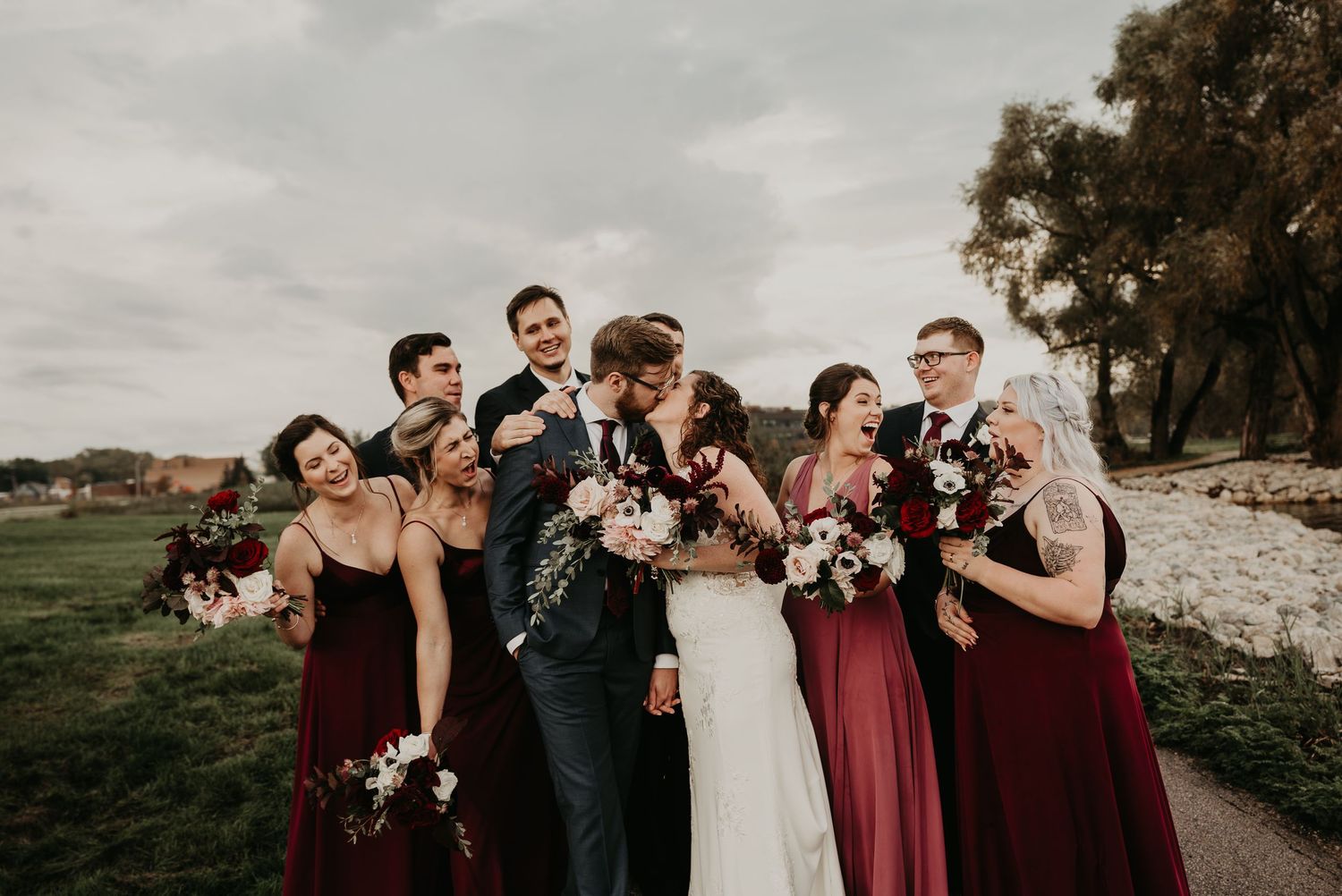 bride and groom kiss while wedding party gasps