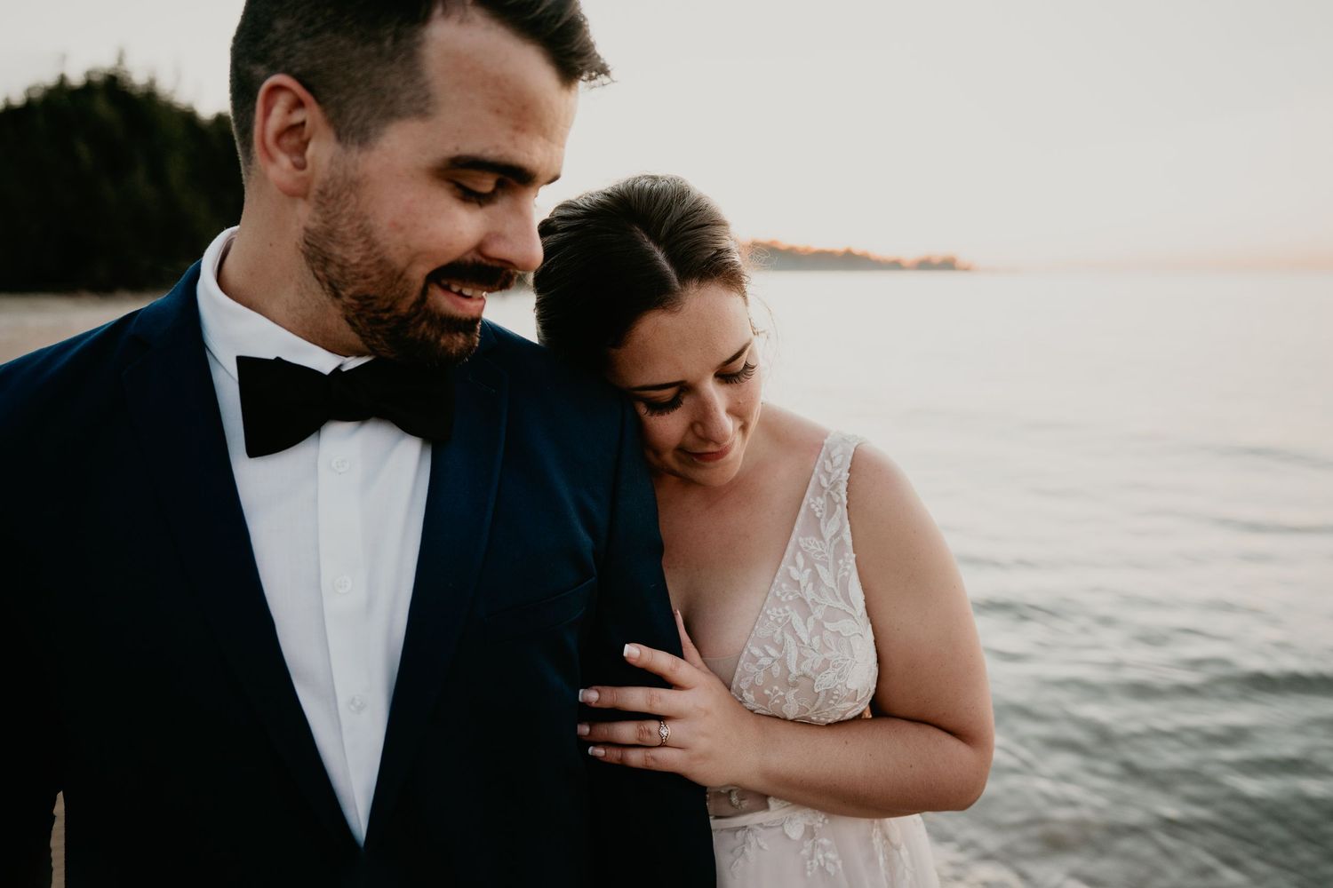 Bride leaning her head against grooms shoulder at the beach