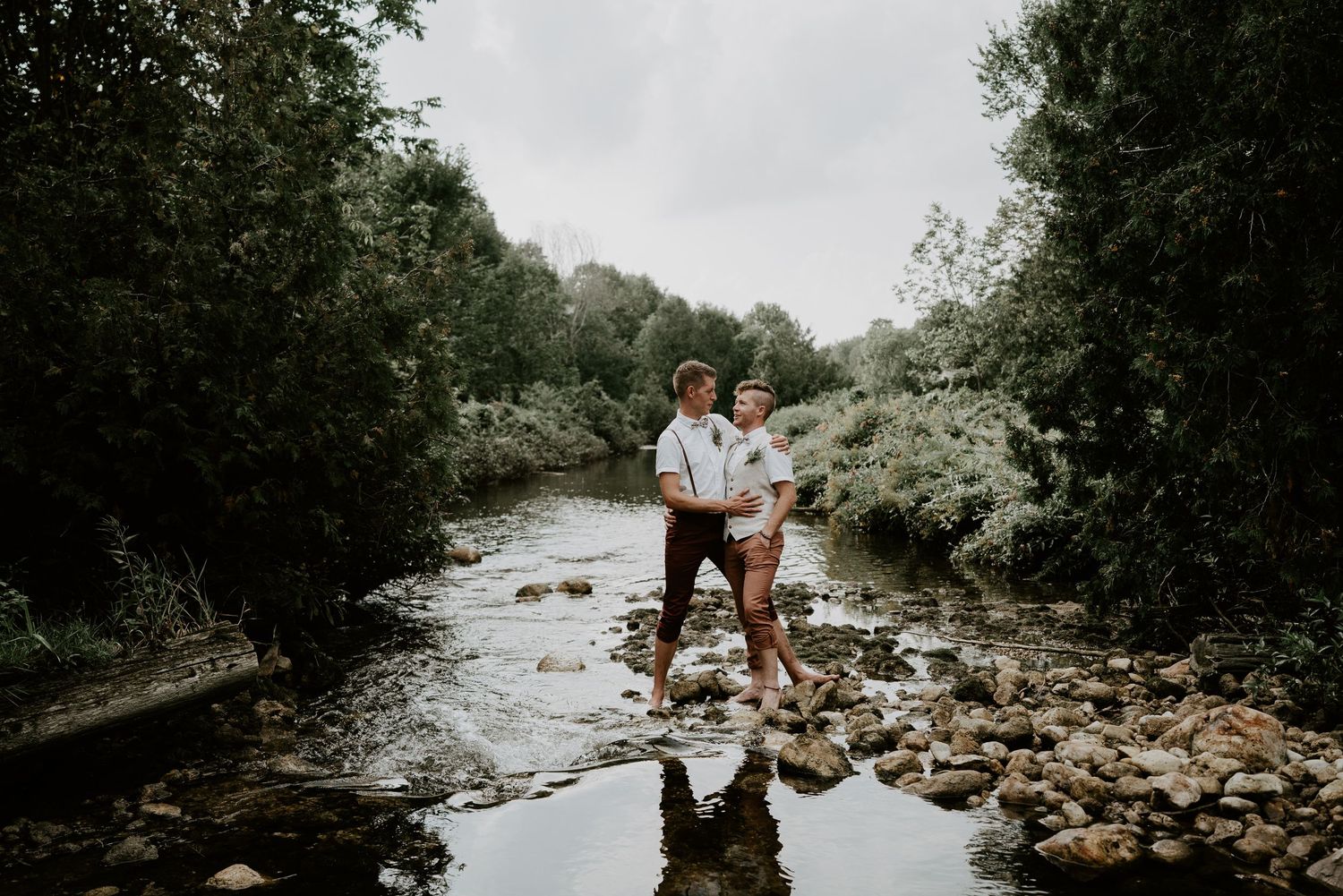 groom and groom in creek on rocks