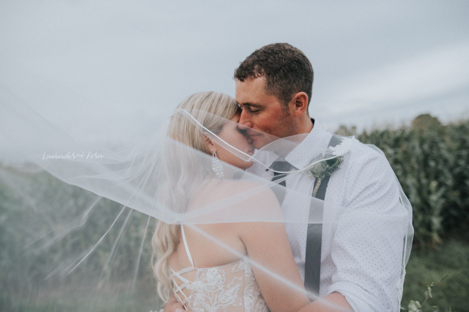 bride and groom embrace on windy veil swept day