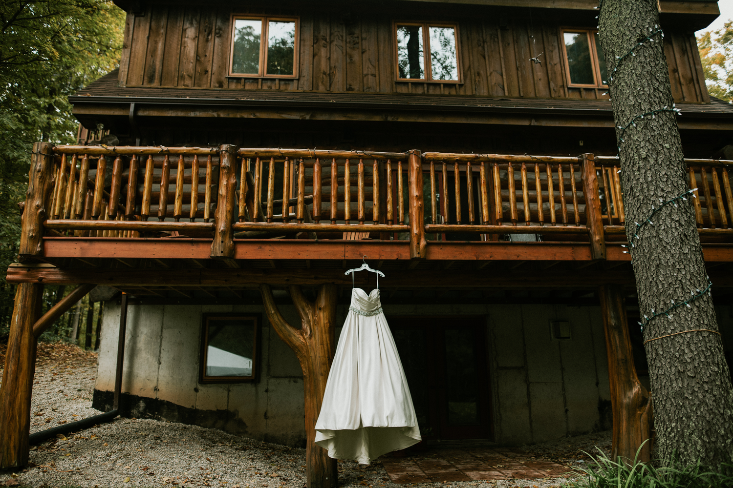 brides wedding gown hanging off of log home balcony