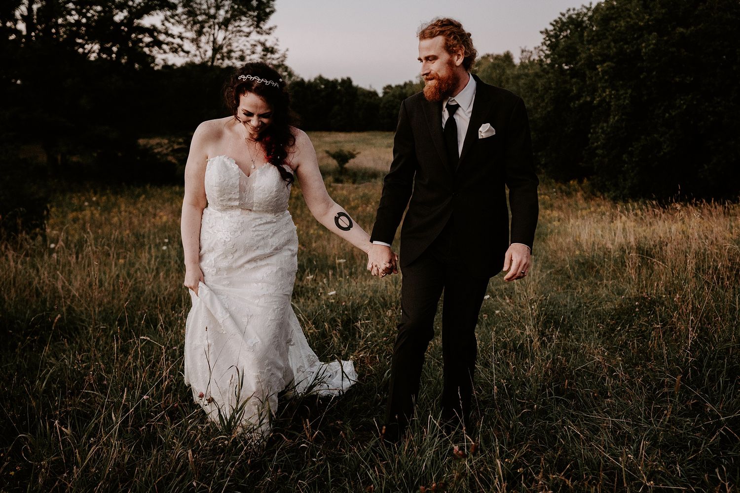 Bride and groom walk uphill in field