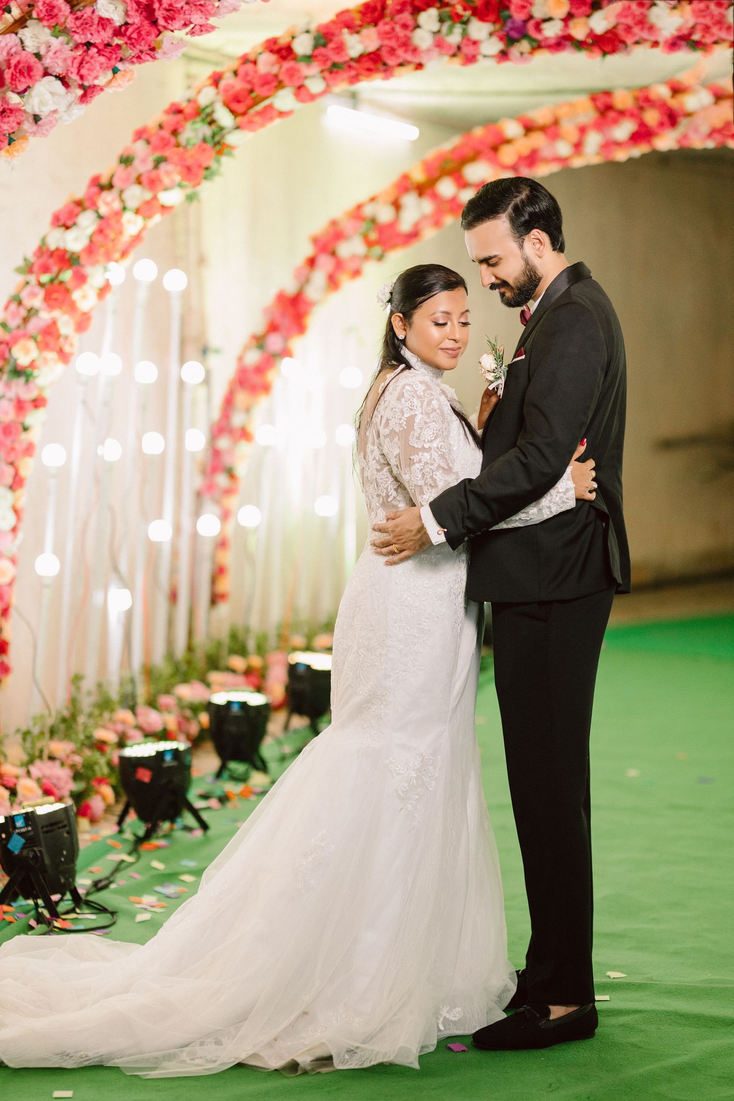Elegant wedding scene with couple dancing under floral decorations and string lights.