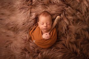 Newborn session baseball theme; baby posed on fur with tiny baseball bat; newborn photography studio South Carolina