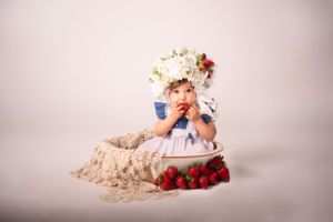 Baby girl in white flower bonnet eating strawberries white backdrop, summer sitter session; Lexington, SC photographer