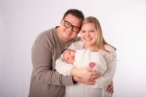 Newborn family photographer Lexington, SC; mom, dad, newborn baby girl posed on white in studio portrait session