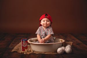 sitter baby photos boy in baseball uniform sitting in bowl with Cracker Jacks & baseballs; Lexington, SC photographer
