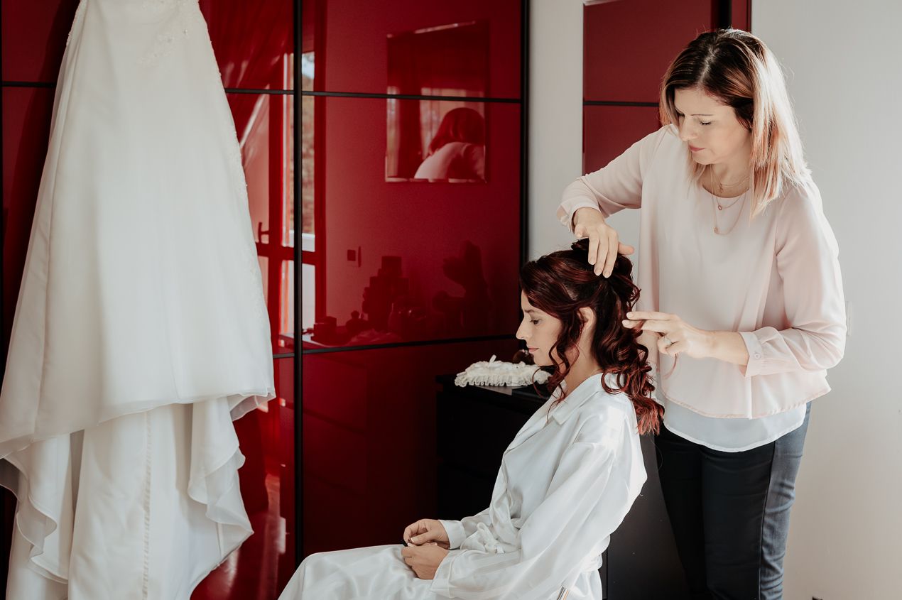 Wedding preparation scene with bridal styling in progress against red accents.