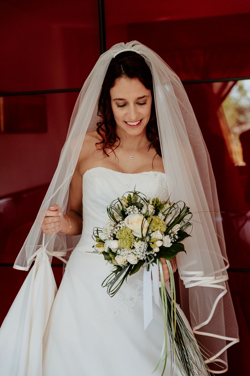 Elegant bride in a white wedding gown holding a bouquet of white and yellow flowers.