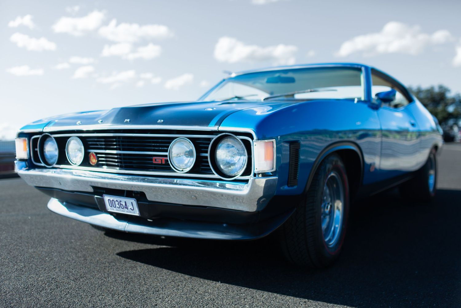 Classic blue Ford XY GT Falcon muscle car photographed from front quarter view on asphalt.