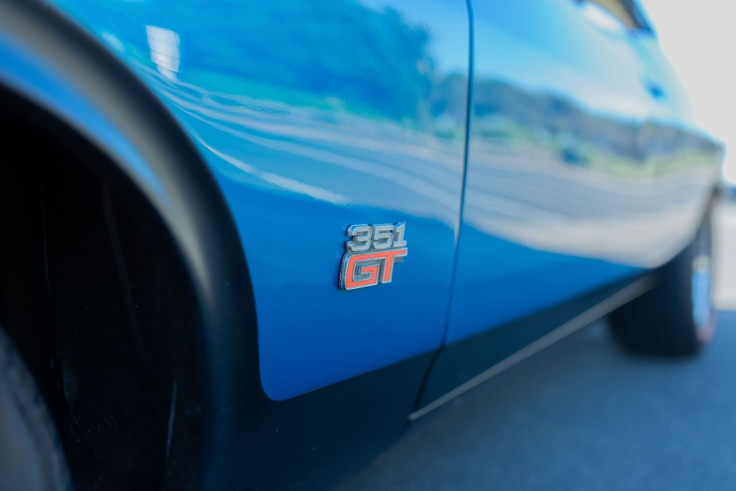 Close up detail shot of GT badge on blue classic muscle car panel.