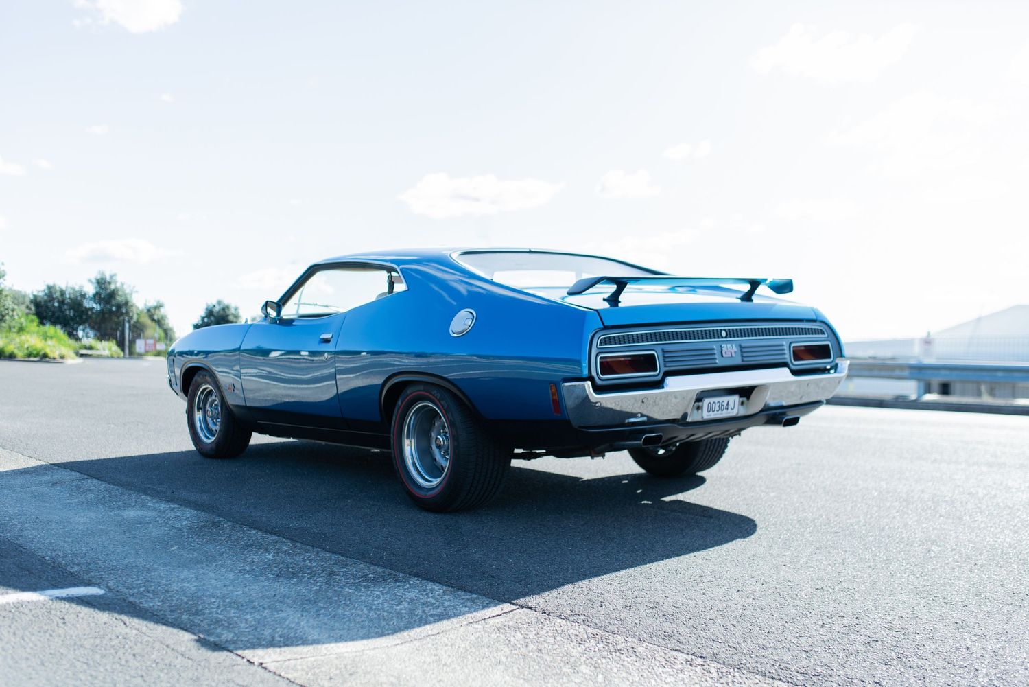 Classic blue Ford Torino GT muscle car photographed from rear quarter view.
