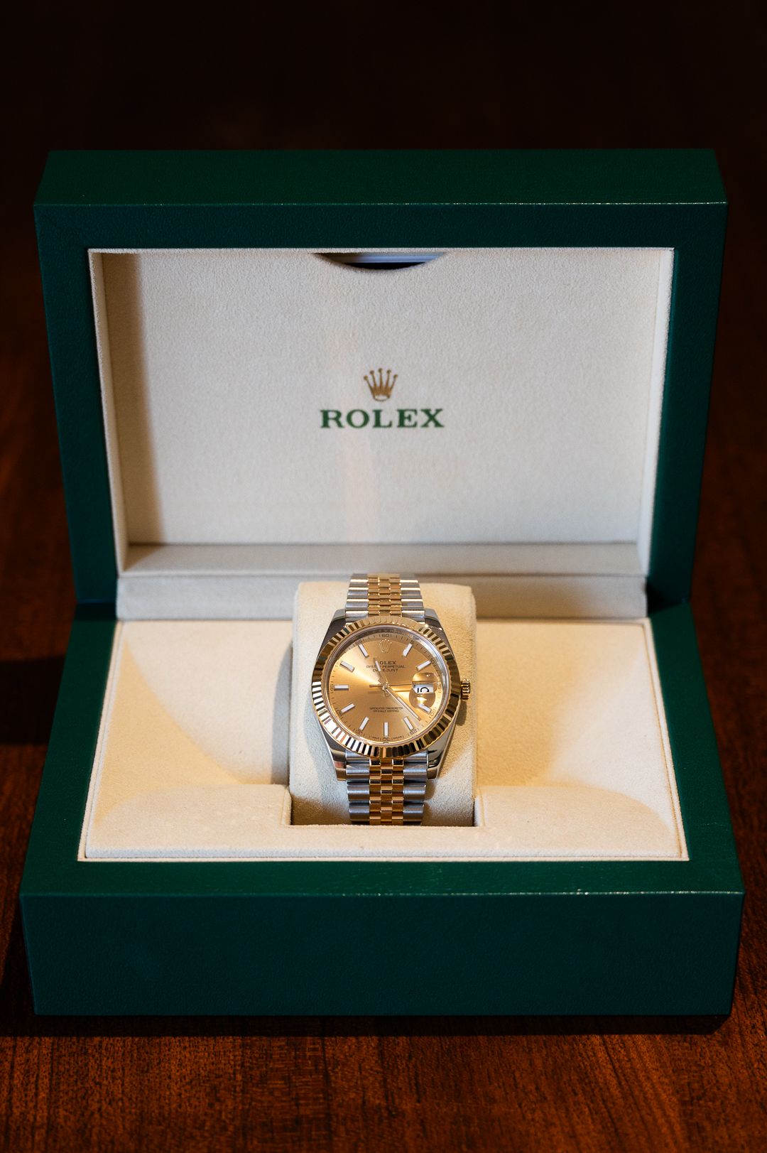 Rolex watch with gold dial displayed in green presentation box.