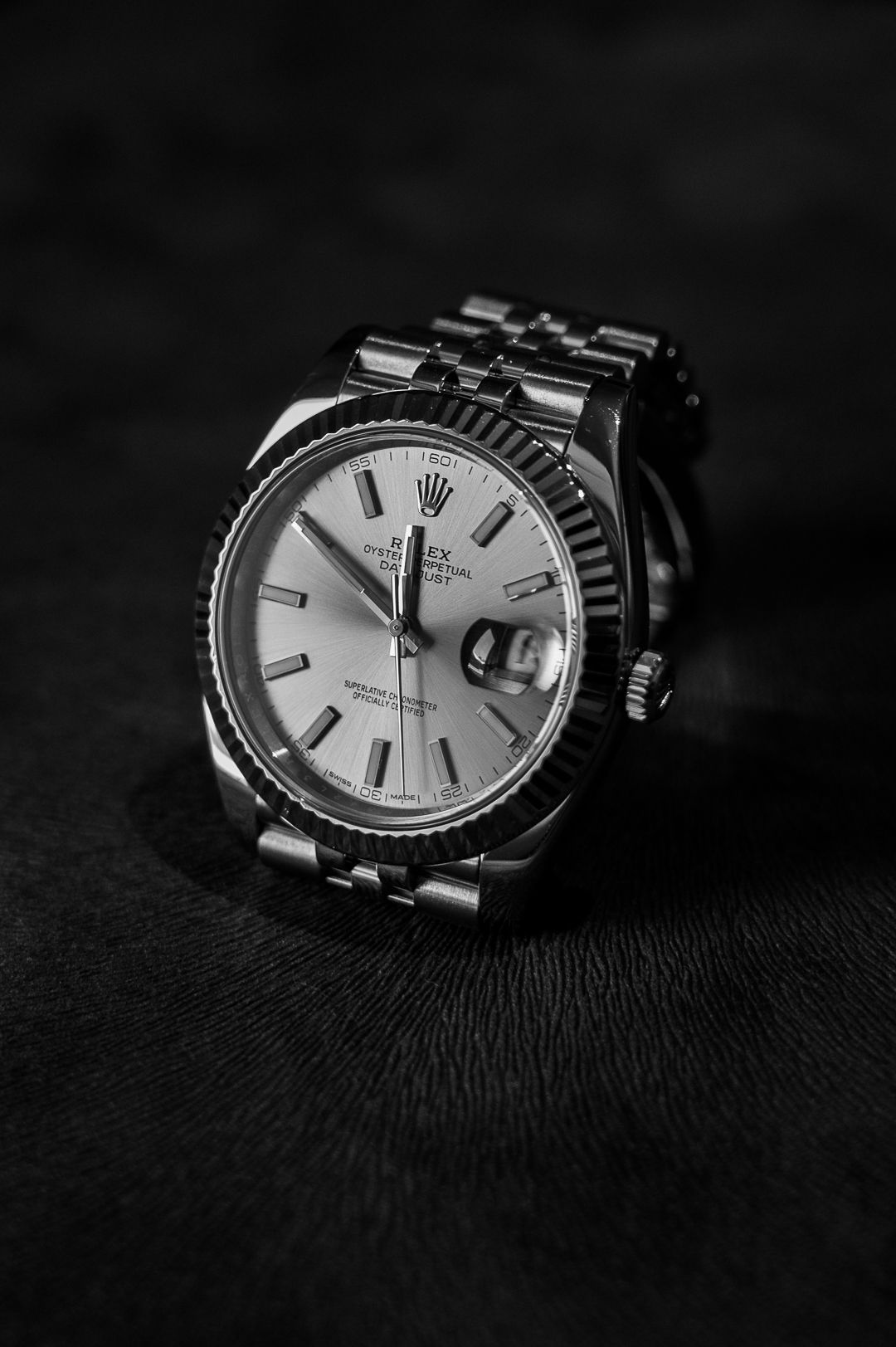 Elegant Rolex with white dial and fluted bezel on dark background.