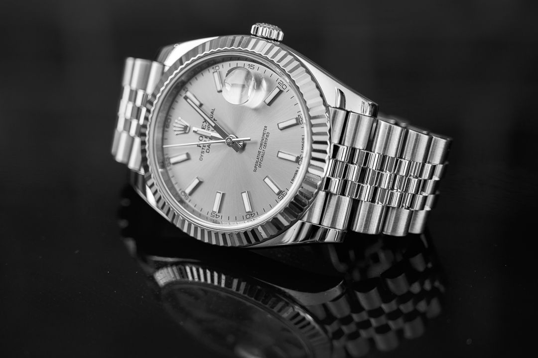 Classic stainless steel Rolex with silver dial photographed in dramatic lighting.
