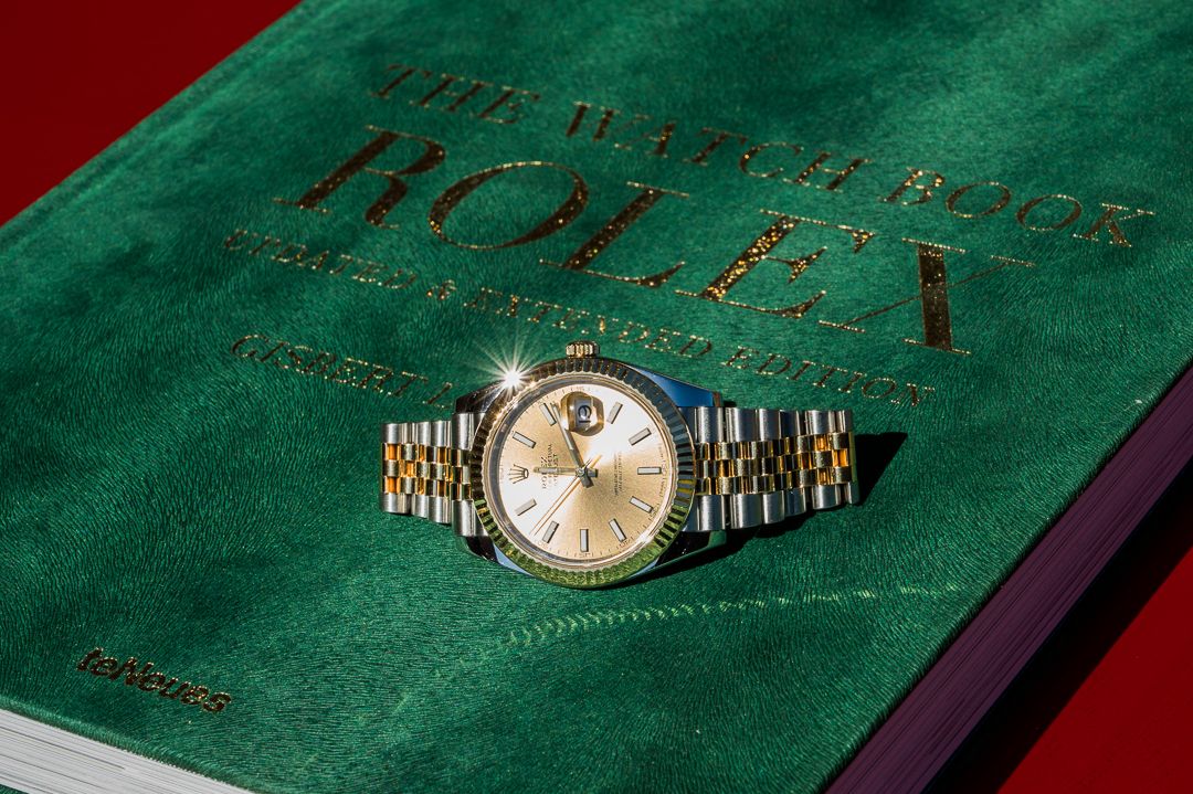 Vintage Rolex watch displayed on green velvet book cover.