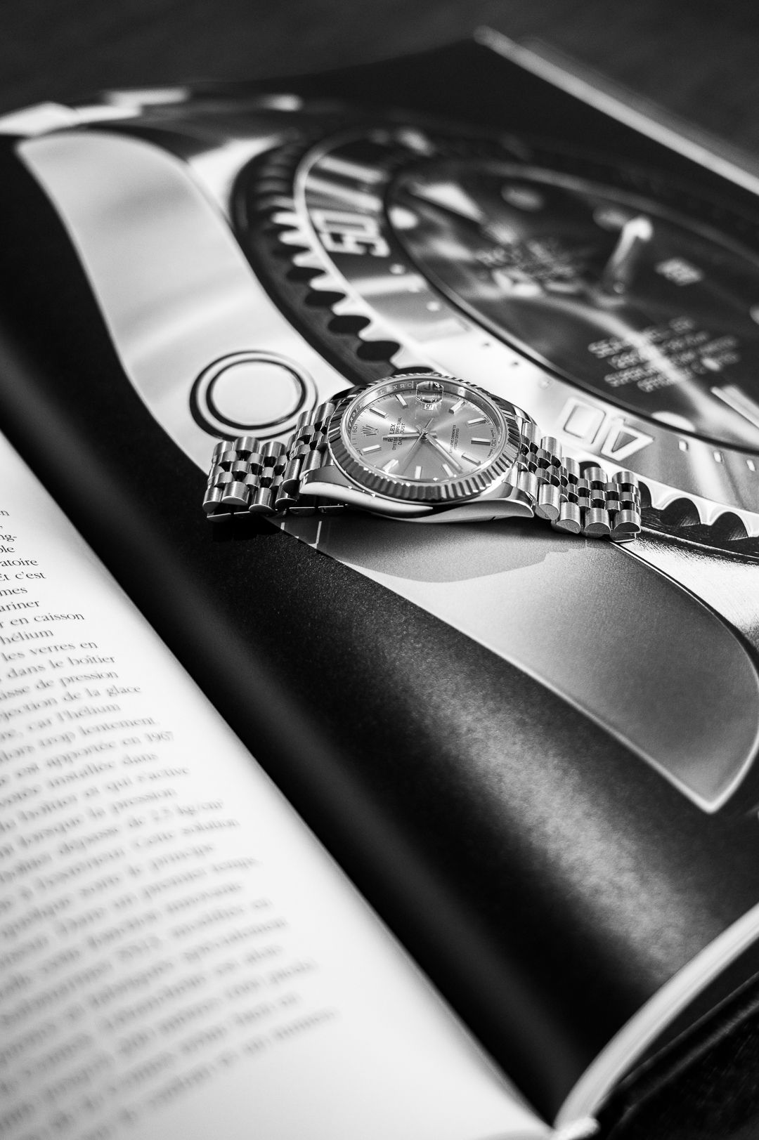 Monochrome image of Rolex timepiece photographed on glossy magazine spread.