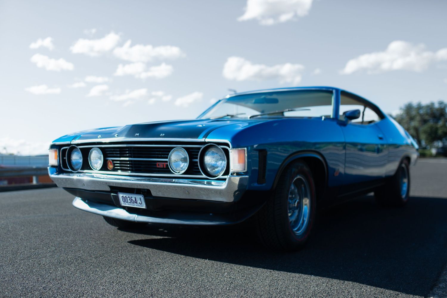 Vintage Ford XY GT Falcon in metallic blue shown from low angle front view.