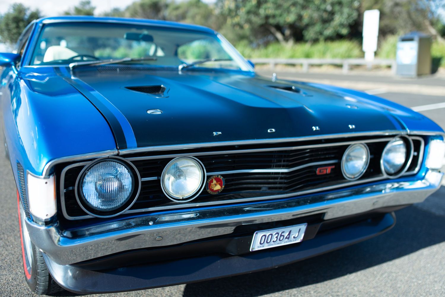 Classic blue Ford muscle car showing detailed front end with quad headlights.