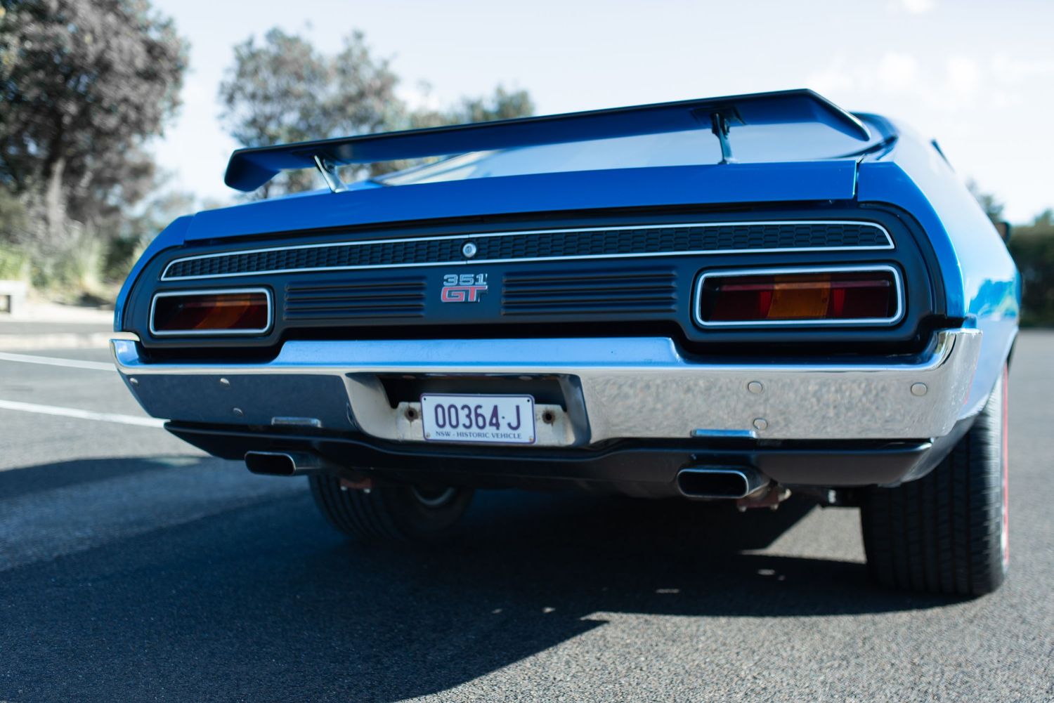 Rear view of a classic Ford Falcon GT showing dual exhaust and taillights.