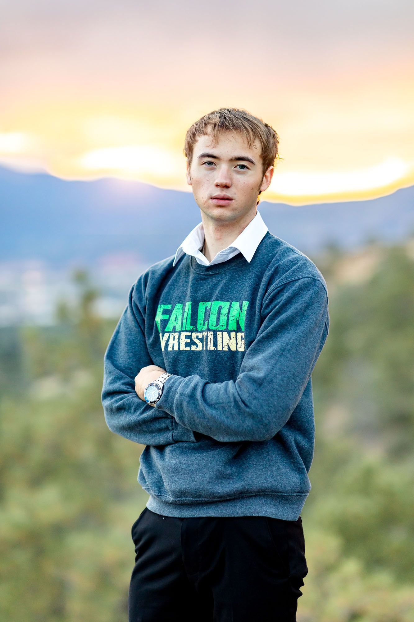 Senior guy in wrestling sweatshirt poses with arms crossed at his senior session at Palmer Park in Colorado Springs.