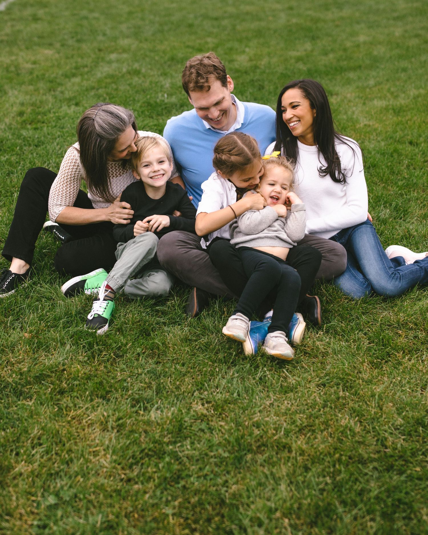Happy family sitting together on grass having fun and laughing.