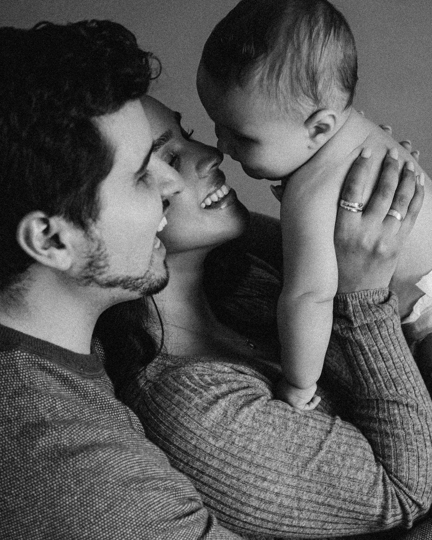 An intimate black and white portrait capturing a family's joyful moment with their baby.