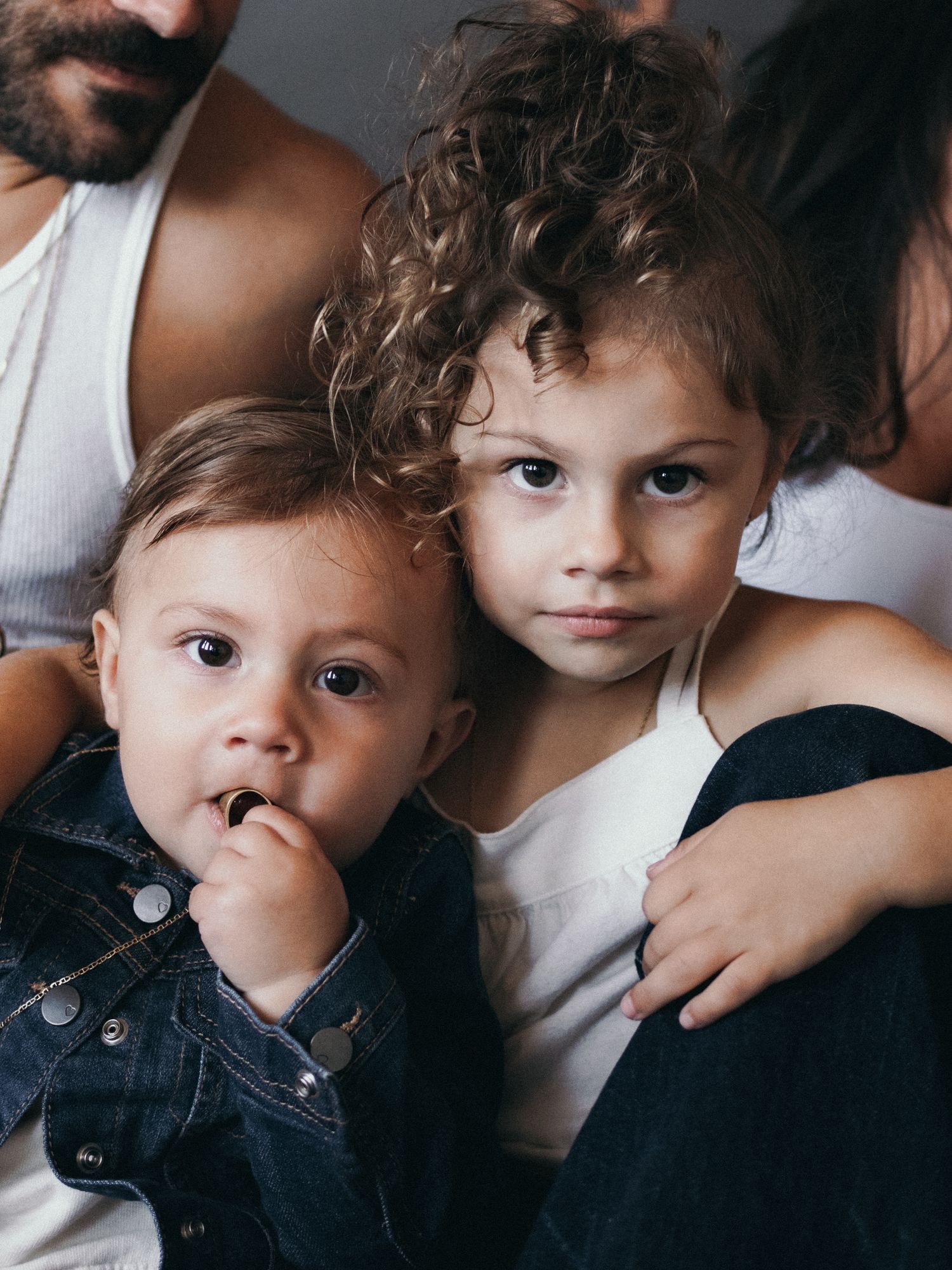 Two young children in casual attire pose together for an intimate portrait.