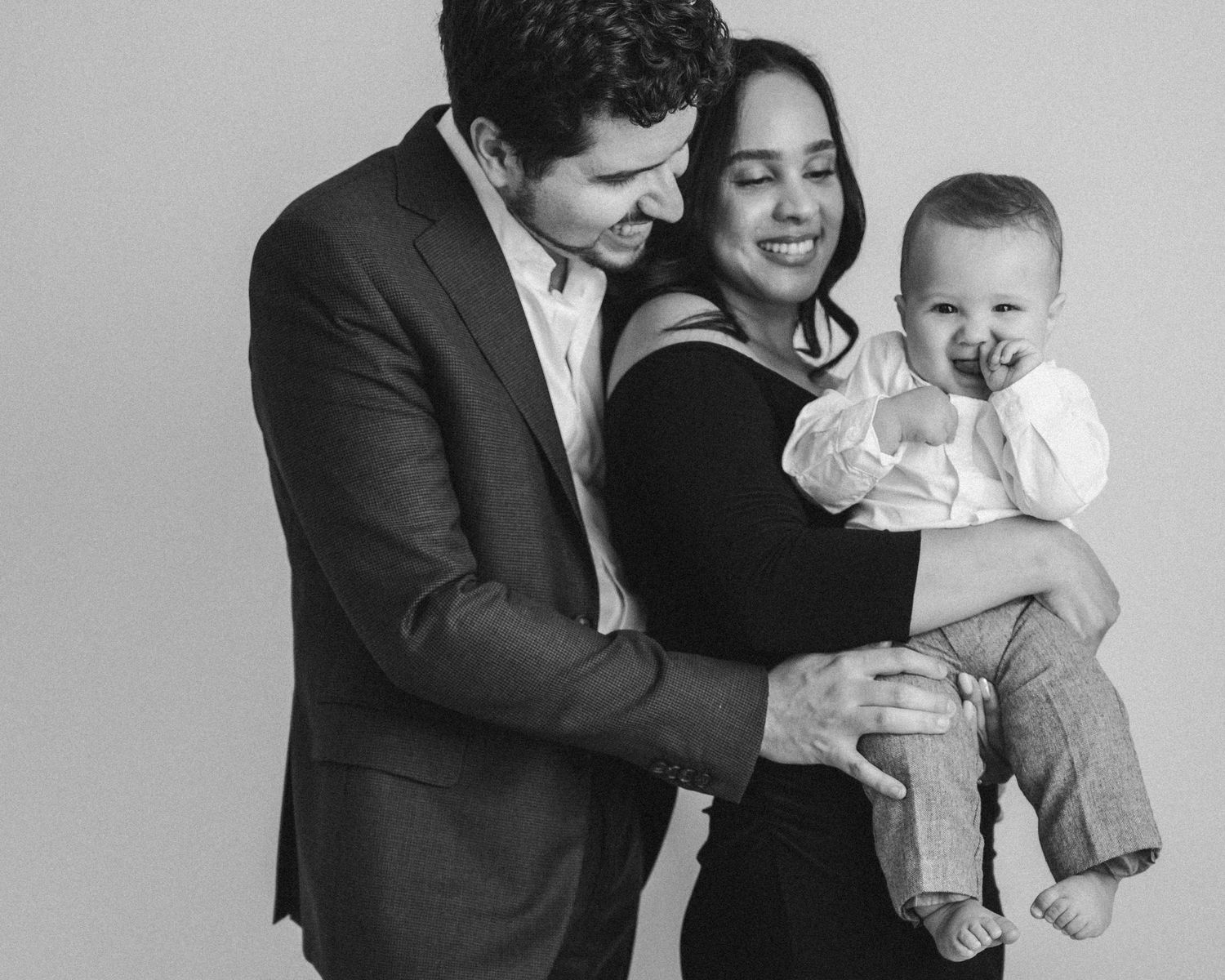 A happy family portrait in black and white with a laughing baby.