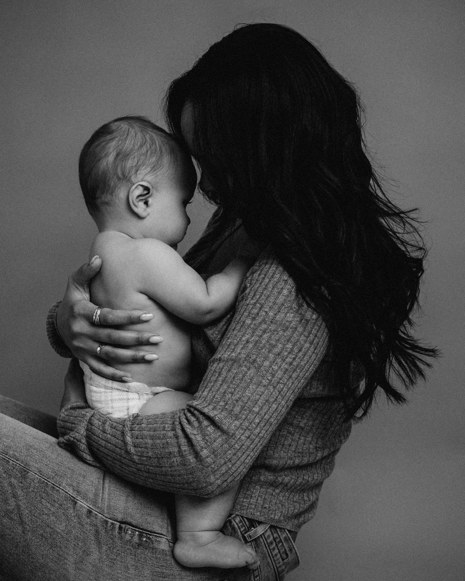 A tender black and white portrait of a parent cradling a baby in a warm embrace.