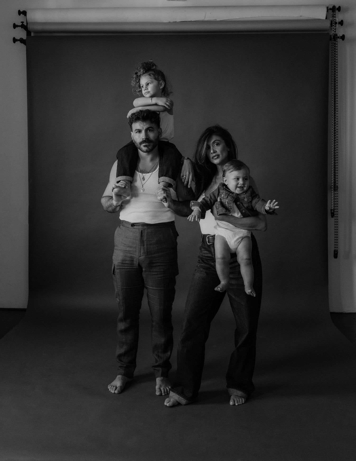 Black and white studio portrait of family with children in playful poses.
