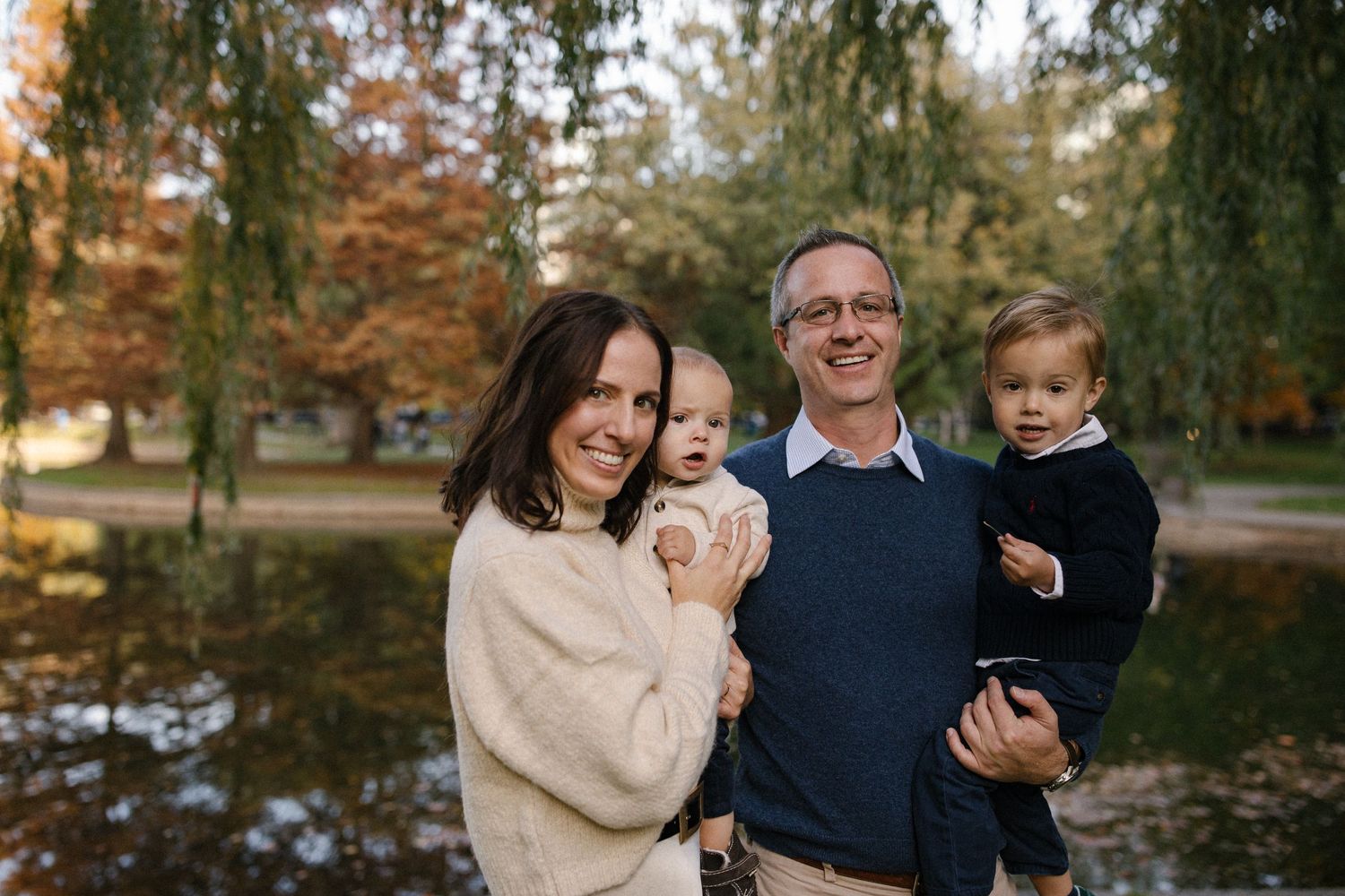 Family spending time together outdoors during fall season near a scenic pond.
