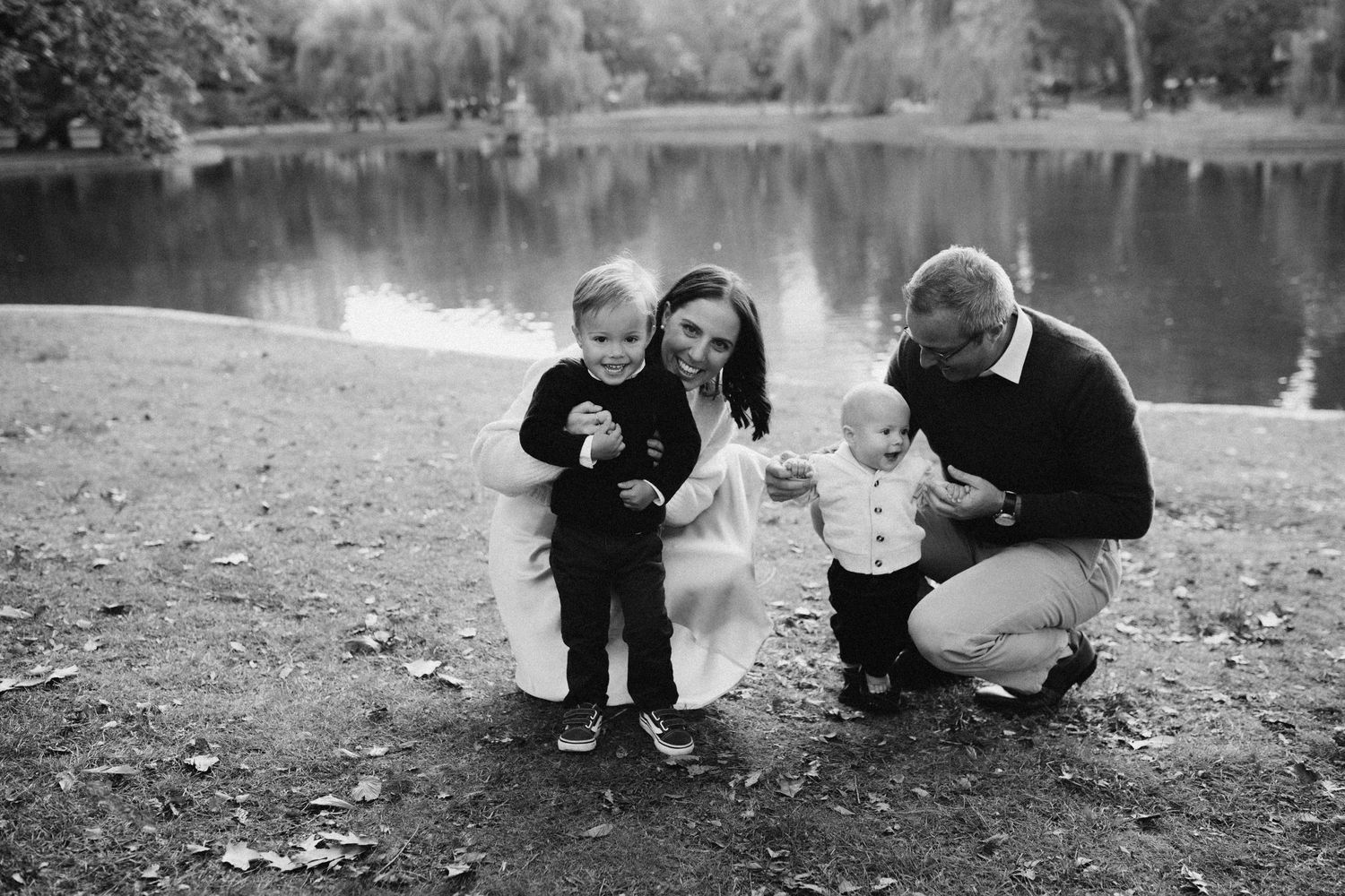 Family enjoying a tender moment together by a peaceful lake on an autumn day.