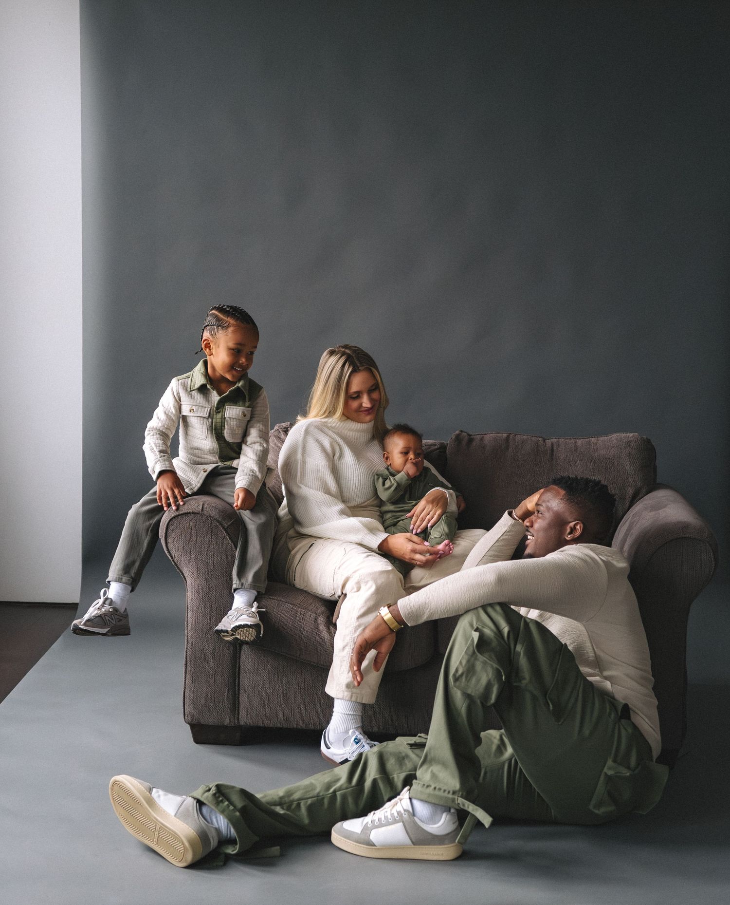 A family relaxes together on a gray couch in a modern minimalist setting.