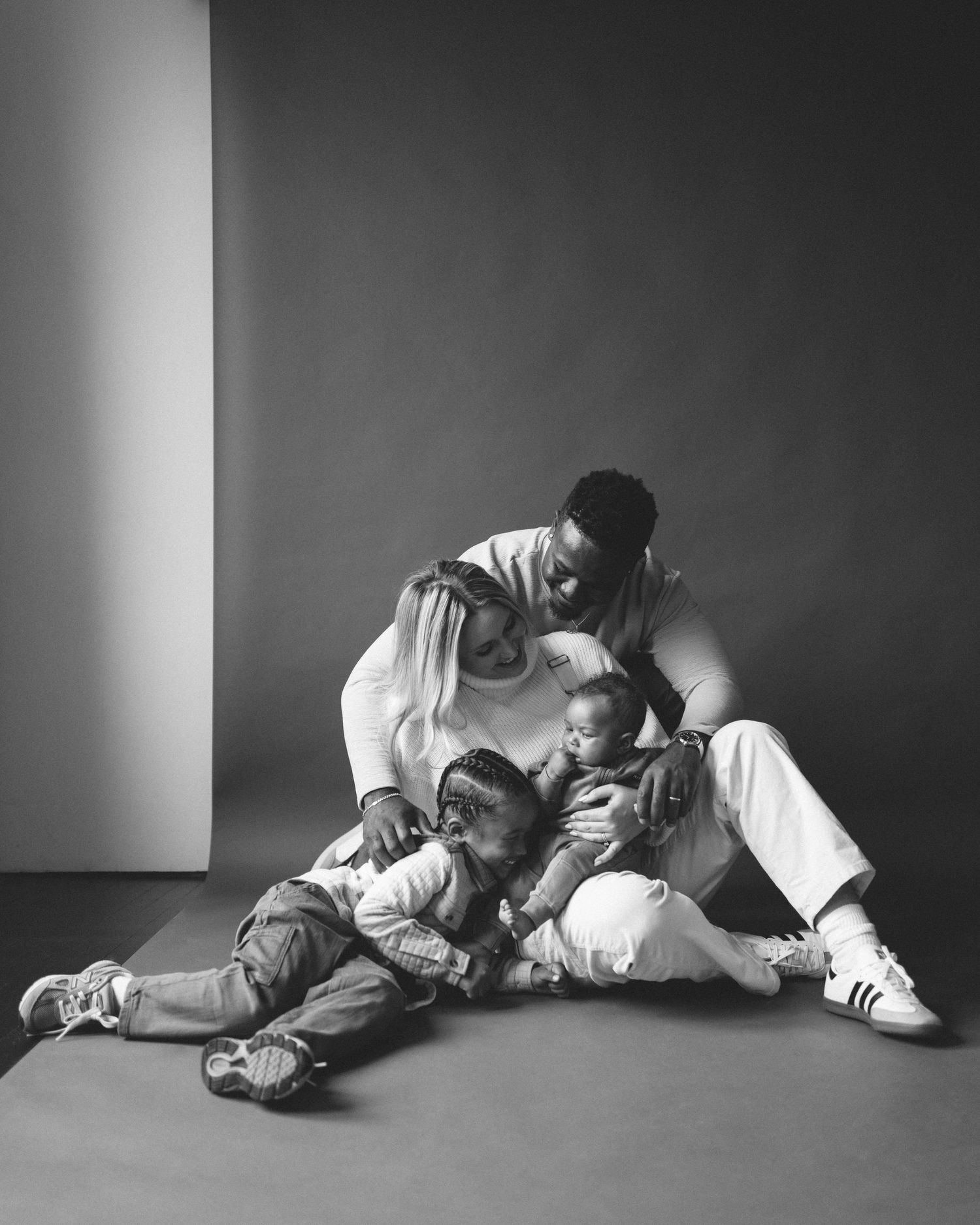 A heartwarming black and white portrait of a parent and child sharing a playful moment on the floor.