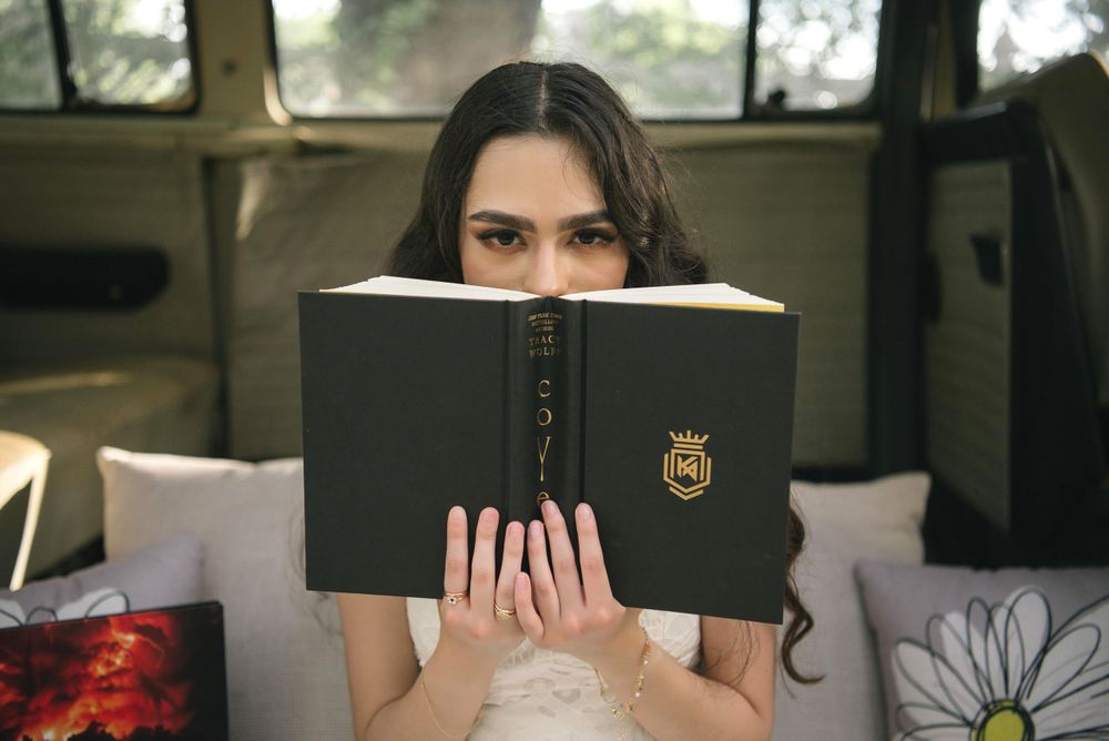 Girl posing behind a book at a casual photo session. Memory Lane Photo Spot. Mission, Texas
