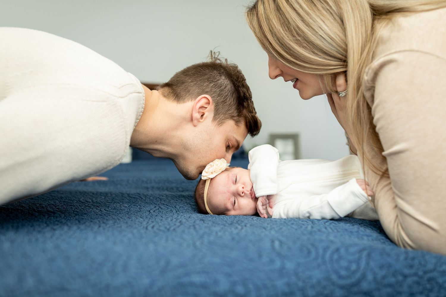 Sweet family moment as parents gaze at their baby on blue bedding.