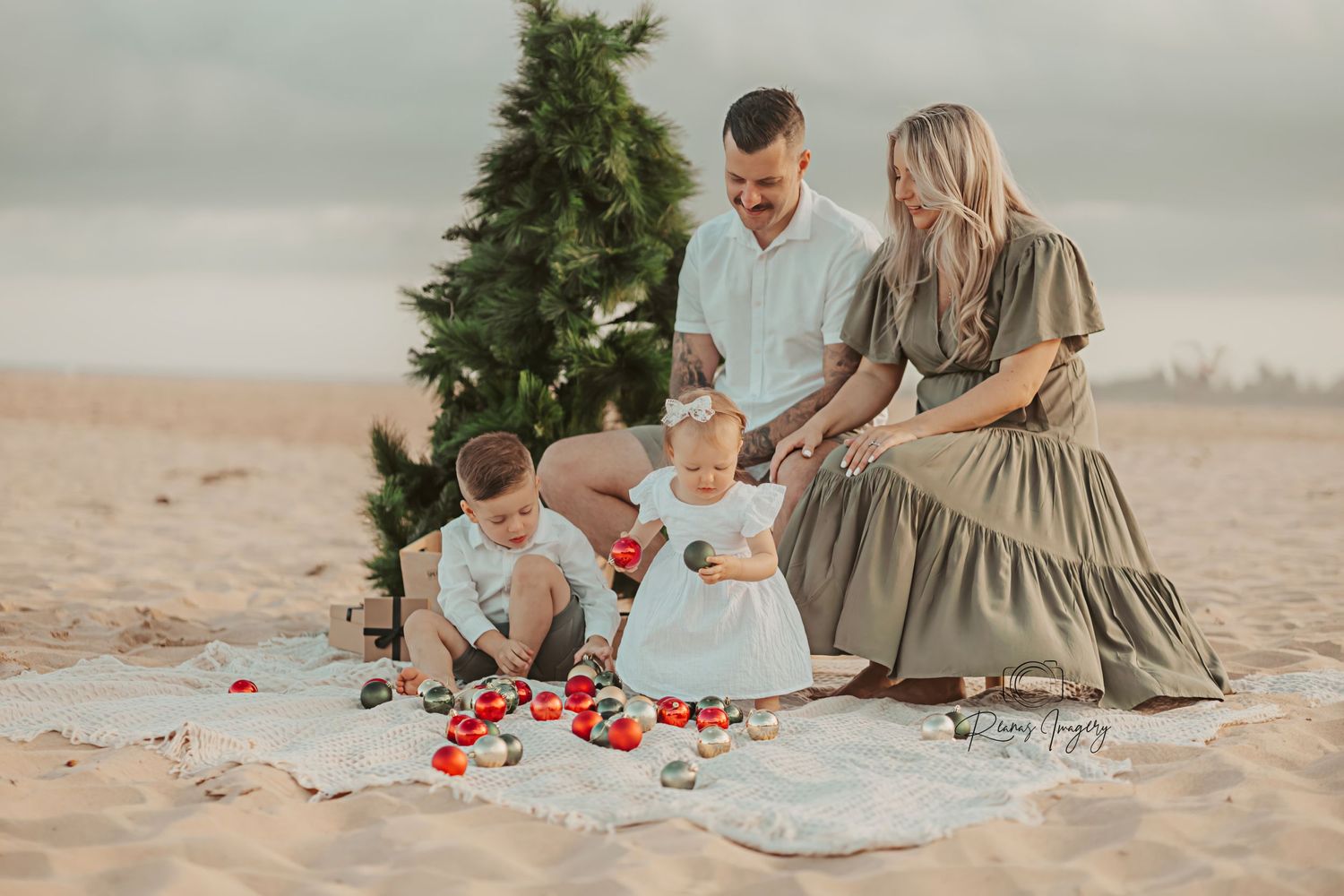 Family of four enjoying a Christmas beach photo session with a festive tree.