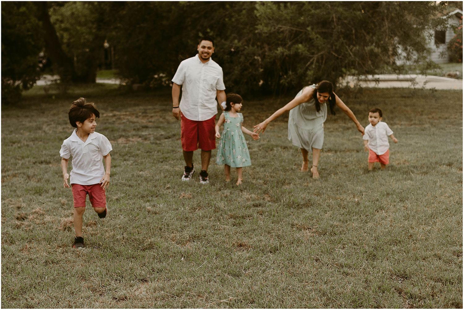 A family plays together on a grassy field during a warm evening.