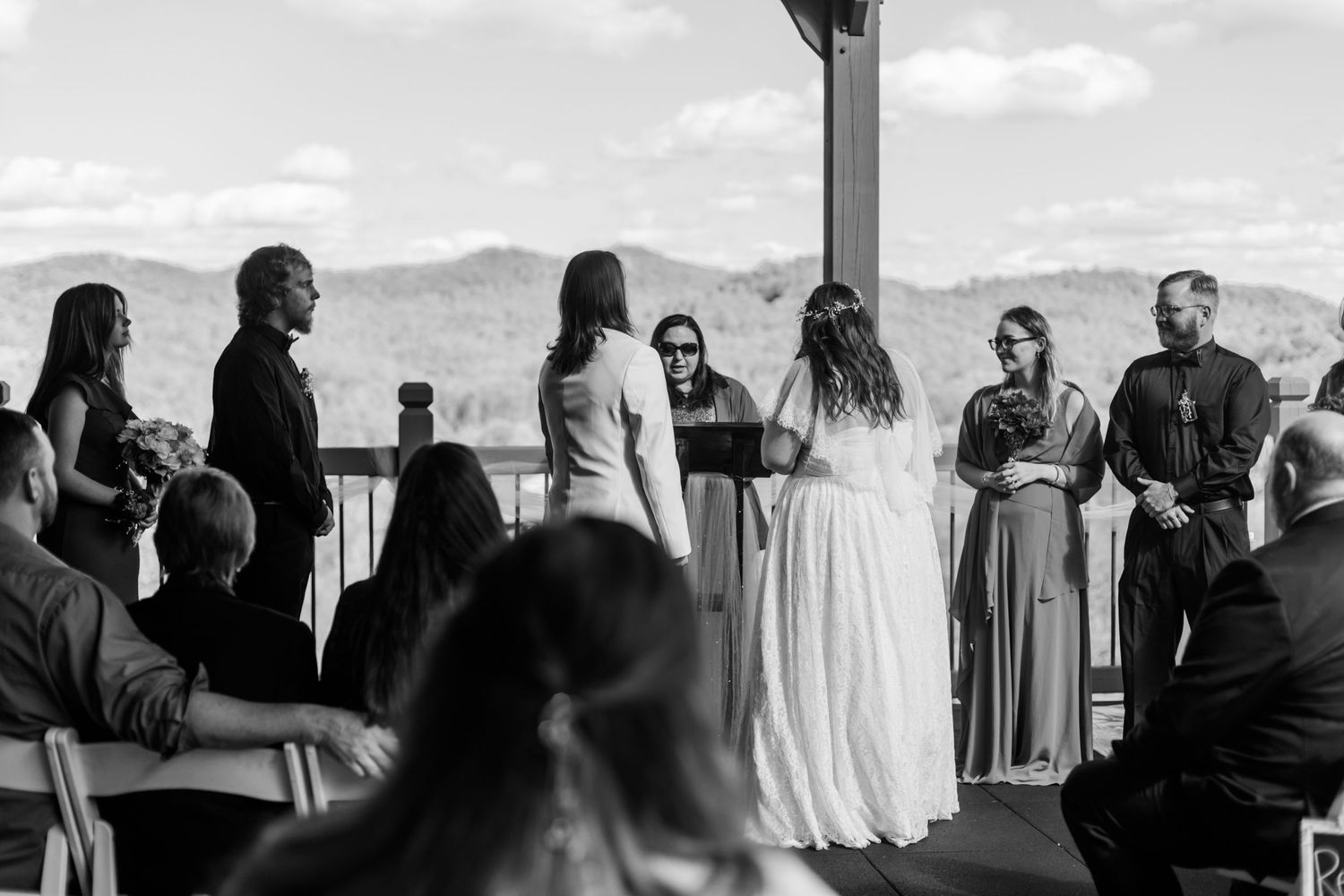Black and white silhouette of wedding guests during an outdoor ceremony.