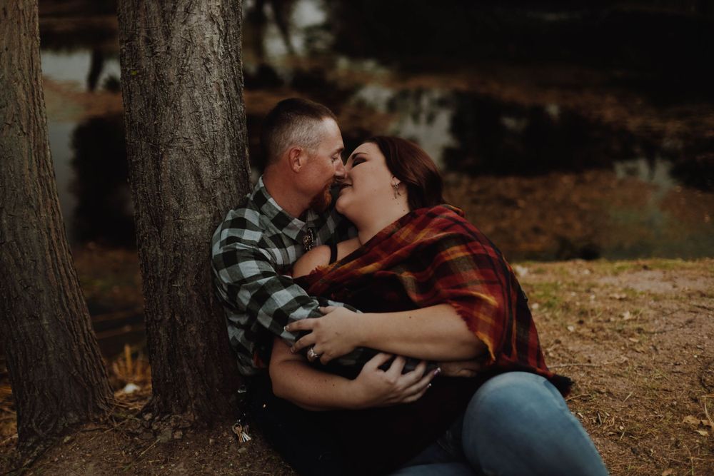 Intimate couple's portrait taken under trees in warm autumn lighting.