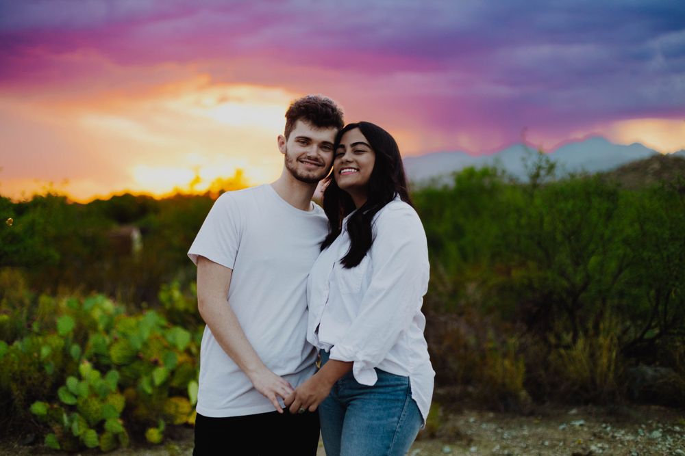 Romantic couple photos against a vibrant purple and orange desert sunset.