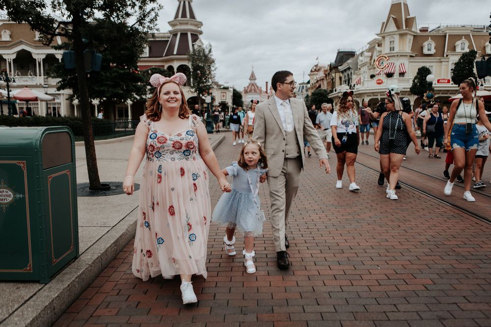 Happy family walks hand in hand down Main Street at Disneyland Paris theme park.