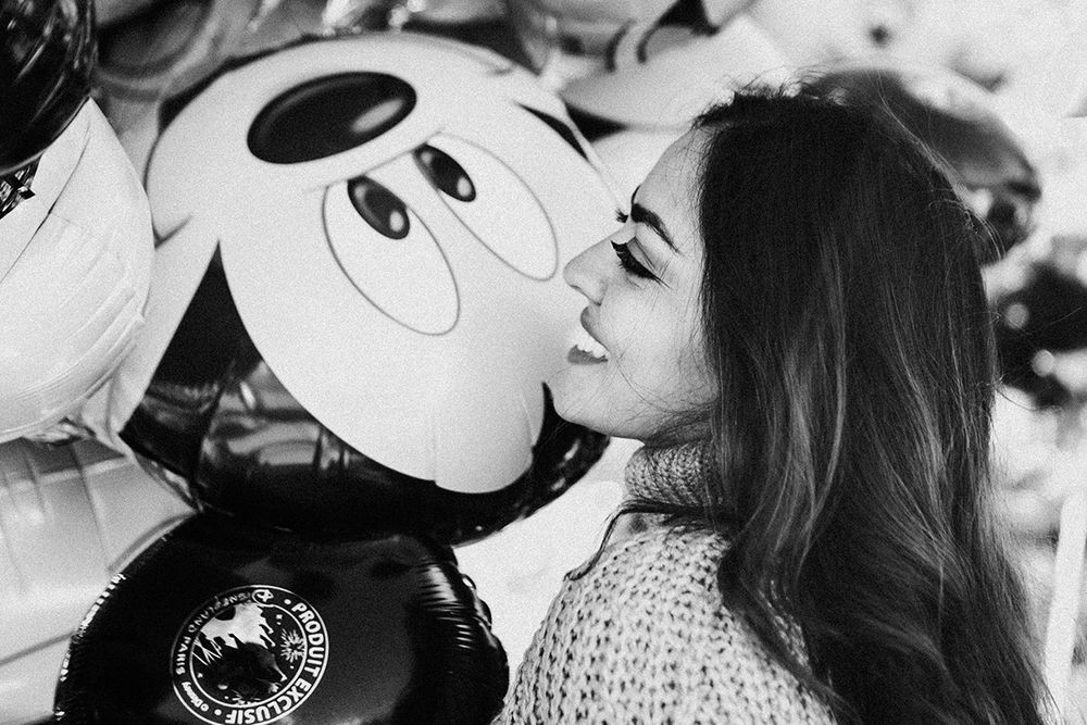 Young woman kissing a Mickey Mouse balloon in a black and white photo at Disneyland.