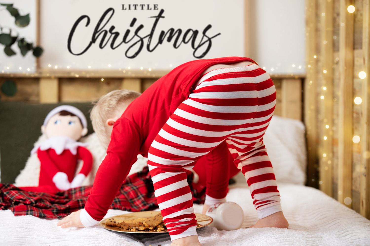 Person in red and striped Christmas pajamas bending down near an Elf on the Shelf doll.