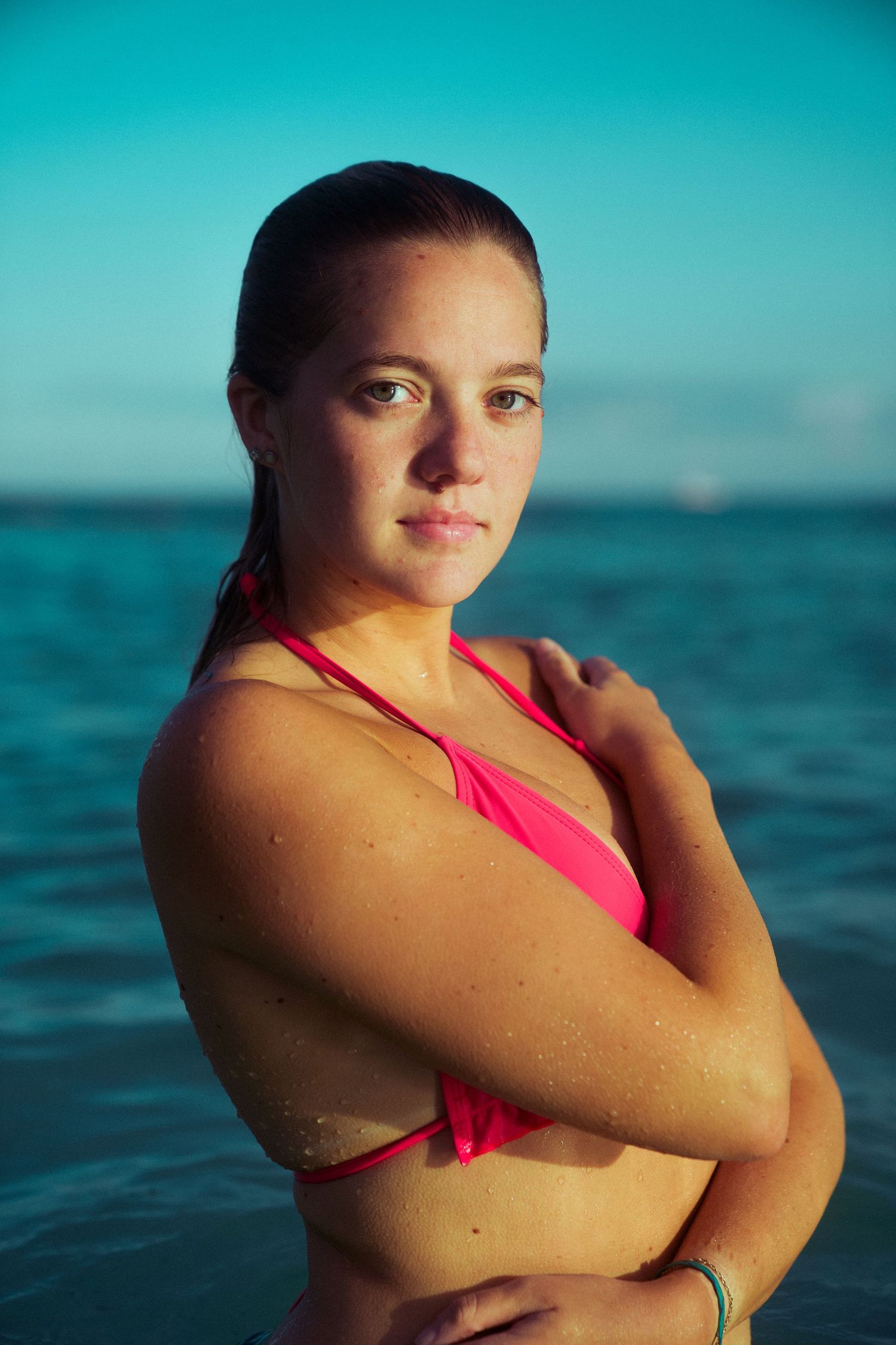 Portrait of swimmer in red swimsuit against vibrant turquoise ocean backdrop.